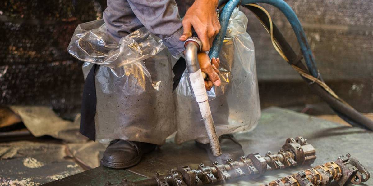 Operaio utilizza la tecnica della sabbiatura criogenica per il trattamento di componenti meccanici a Modena. Il processo di pulizia avviene utilizzando ghiaccio secco, che rimuove in modo sicuro vernici, grasso e ruggine dalle superfici senza danneggiarle, mantenendo intatti i componenti.