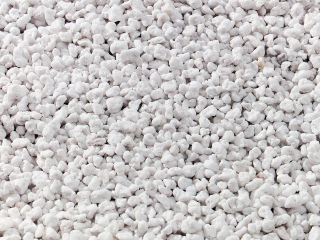 Vista ravvicinata di granuli di perlite utilizzati per l'insufflaggio in pareti e intercapedini per l'isolamento termico a Mantova. La perlite è un materiale naturale che migliora l'efficienza energetica degli edifici, riducendo la dispersione di calore e migliorando il comfort abitativo.