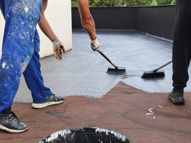 Operai applicano una membrana liquida bituminosa su una superficie a Parma per garantire impermeabilizzazione e protezione dagli agenti atmosferici.