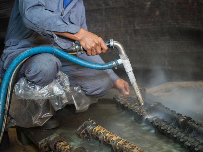 Operatore esegue la sabbiatura criogenica su componenti meccanici a Parma, utilizzando ghiaccio secco per la pulizia senza residui abrasivi.