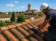 Tecnico specializzato che ispeziona un tetto in tegole a Goito durante una calda giornata estiva per verificare eventuali danni causati dal sole prima delle piogge autunnali.